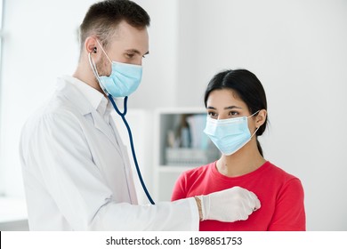 doctor with a stethoscope examines a patient wearing a medical mask breathing lungs health - Shutterstock ID 1898851753