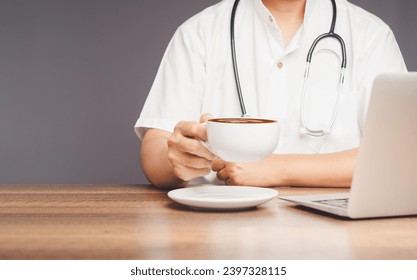 A doctor with a stethoscope holding a coffee cup while sitting at the desk. Medical, Beverage, and relaxation concepts. - Powered by Shutterstock