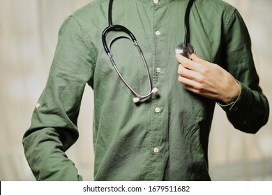 Doctor with a stethoscope. Doctor on the neck with a stethoscope. The medicine. Virus. Cold. Coronavirus. Pandemic. Doctor in a green shirt. - Shutterstock ID 1679511682