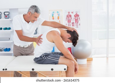 Doctor stretching a young man back in medical office - Powered by Shutterstock