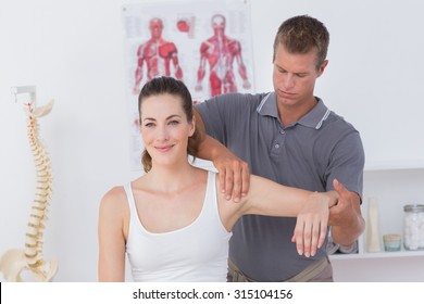 Doctor stretching a young woman arm in medical office
