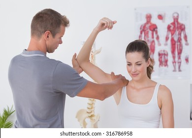 Doctor stretching a young woman arm in medical office
