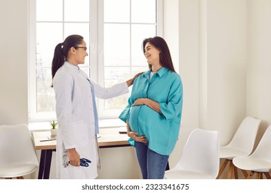 Doctor supporting pregnant woman. Pregnant lady visits doctor at clinic. Friendly, smiling obstetrician in white medical coat puts hand on shoulder of young pregnant girl. Pregnancy healthcare concept - Powered by Shutterstock