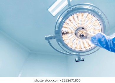 Doctor or surgeon in blue gown holding surgical lamp to adjust light inside operating theatre with space in background.People did surgery in hospital.Nurse with medical glove in operating room. - Powered by Shutterstock