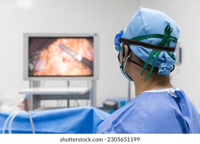 Doctor or surgeon in blue uniform looking at monitor screen in operating room at hospital.Minimal invasive gall bladder surgery in stone.Medical technology with white space.Computer assist device.