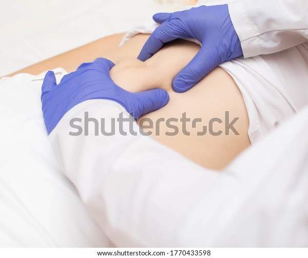 Doctor surgeon examines the\
stomach of a girl patient for the presence of umbilical hernia.\
Abdominal wall disease concept with umbilical hernia, reinforced\
hernia