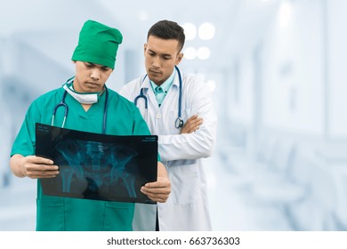 Doctor And Surgeon Examining Xray Film, Diagnose Patient 's Waist Bone Injury. Surgery Operation And Medical Concept.