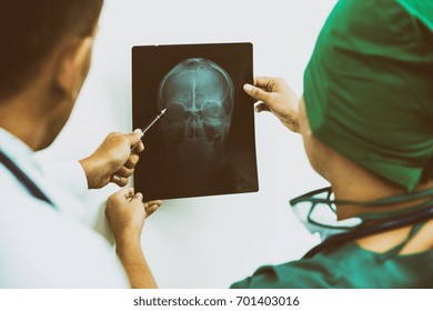 Doctor And Surgeon Examining X-ray Film Of Patient 's Head For Brain, Skull Or Eye Injury. Medical Diagnosis And Surgical Treatment Concept. 