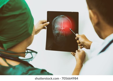 Doctor And Surgeon Examining X-ray Film Of Patient 's Head For Brain, Skull Or Eye Injury. Medical Diagnosis And Surgical Treatment Concept. 