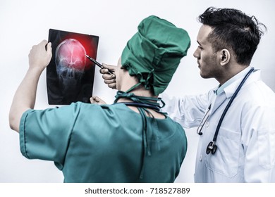 Doctor And Surgeon Examining X-ray Film Of Patient 's Head For Brain, Skull Or Eye Injury . Medical Injury Diagnosis And Brain Injury Treatment Concept.