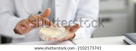 Doctor surgeon holding breast silicone implant in clinic. Breast enlargement surgery concept