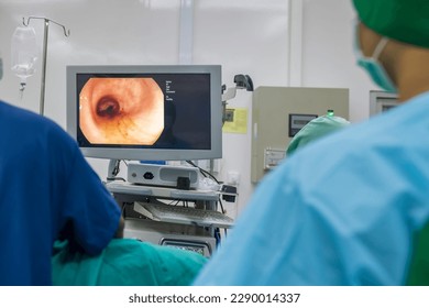 A doctor or surgeon in a light blue protective gown did a colonoscopy or gastroscopy inside operating theatre in the hospital.EGD technology for cancer screening.Blur green background and foreground. - Powered by Shutterstock