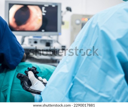 A doctor or surgeon in a light blue protective gown did a colonoscopy or gastroscopy inside operating theatre in the hospital.EGD technology for cancer screening.Blur green background and foreground. 商業照片 © 