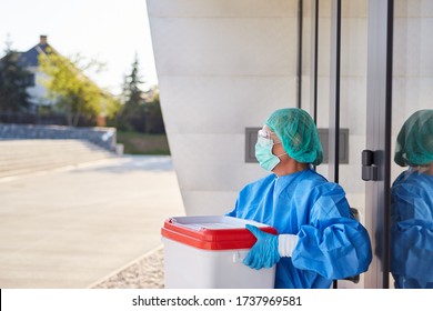 Doctor or surgeon with organ transport after organ donation for surgery in front of clinic entrance in protective clothing - Shutterstock ID 1737969581