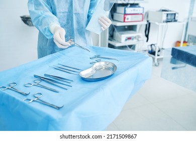 Doctor In Surgical Gown Putting Necessary Tools Into The Tray