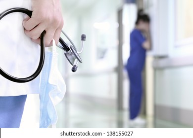 Doctor With Surgical Mask And A Stethoscope In A Hospital Hallway And Crying Woman. The Concept Of An Unsuccessful Operation.