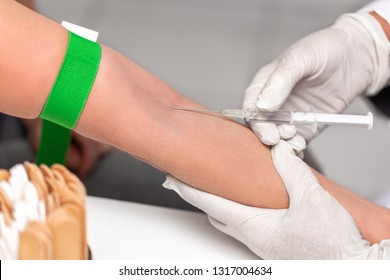 Doctor with a syringe, blood sampling or drawing or infusion on medical office, closeup