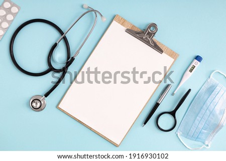 Doctor table with stethoscope, pills, thermometer and medical mask  top view