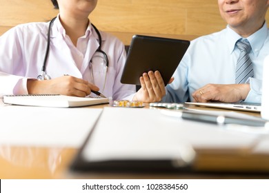 Doctor take care use computer tablet, Patient listening intently to a male doctor explaining patient symptoms or asking a question as they discuss paperwork together in a consultation