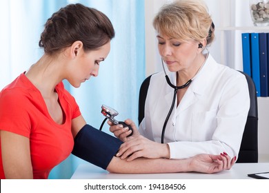 Doctor Taking Blood Pressure Of Female Patient At Office