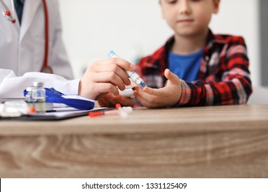 Doctor Taking Blood Sample Of Diabetic Child In Clinic