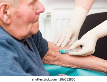 Doctor Taking Blood Sample From Elderly Patient To Monitor Anticoagulant Treatment.