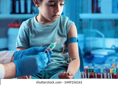 Doctor taking blood sample test of a little boy in the clinic / technician making blood tests on a young boy in the laboratory of blood extractions