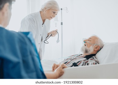 Doctor Taking Care Of Dying Senior Patient With Oxygen Mask