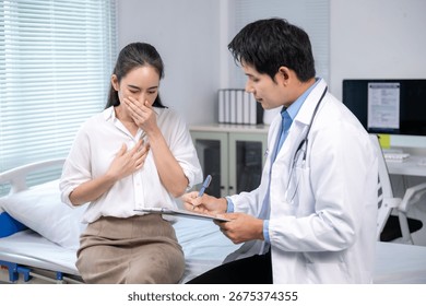 Doctor taking notes while examining a female patient suffering from nausea in a medical office