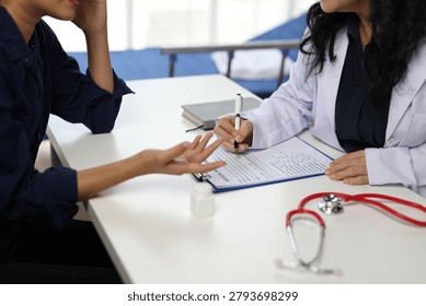 Doctor taking notes while listening to patient explaining symptoms.