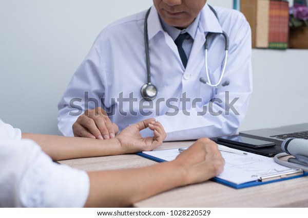 Doctor taking patient\'s pulse at outpatient department\
in hospital. Doctor taking physical examination of female patient\
in clinic, close up