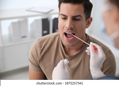 Doctor Taking Sample For DNA Test From Man In Clinic