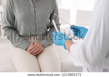 Doctor taking sample for STD testing from woman in clinic, closeup