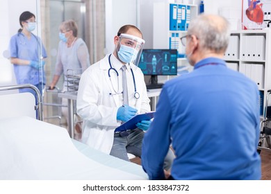 Doctor talking about covid infection with senior patient during treatment consultation in clinic. Modern private hospital Practitioner physician appointment. - Shutterstock ID 1833847372