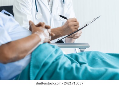 Doctor talking to elderly patient on the bed in hospital. - Powered by Shutterstock