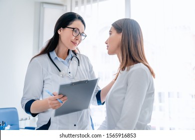 Doctor talking to female patient in working cabinet at hospital - Powered by Shutterstock
