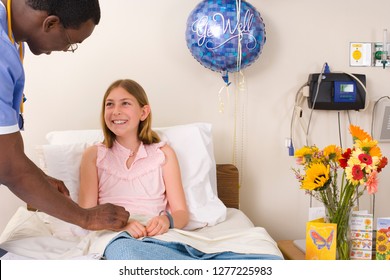 Doctor Talking To Girl Sitting In Hospital Bed With Get Well Balloons