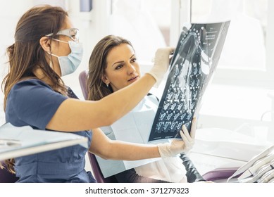 Doctor Talking With Her Patient And Teaching A Radiograph. Dentist Concept.