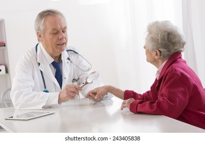 Doctor Talking To His Female Senior Patient At The Office