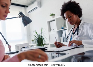 Doctor Talking With Patient At Desk In Medical Office. Health Care Concept, Medical Insurance. Womens Health.