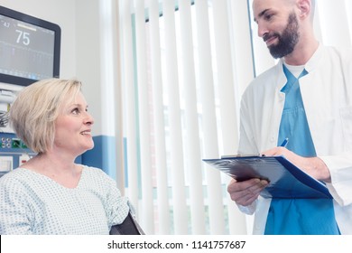 Doctor Talking To Patient In Recovery Room Of Hospital After Awaking From Treatment Or Surgery