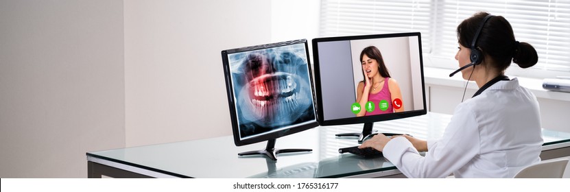 Doctor Talking To Patient Through Video Chat On Laptop At Desk