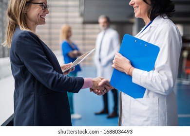 Doctor talking to pharmaceutical sales representative, shaking hands.