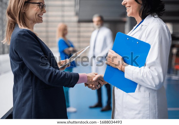 Doctor talking to pharmaceutical sales\
representative, shaking\
hands.