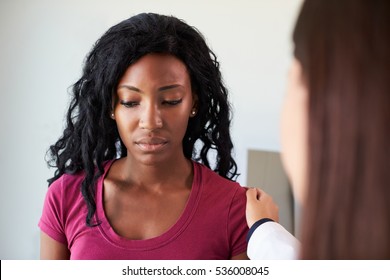 Doctor Talking To Unhappy Female Patient In Exam Room