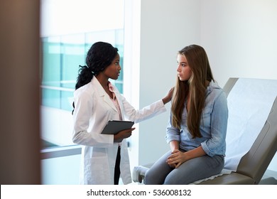 Doctor Talking To Unhappy Teenage Patient In Exam Room