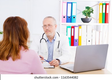 Doctor Is Talking With Woman Patient And Sitting In Medical Office.Man In White Uniform. Medical Insurance. Copy Space. Quality Medicine Concept.