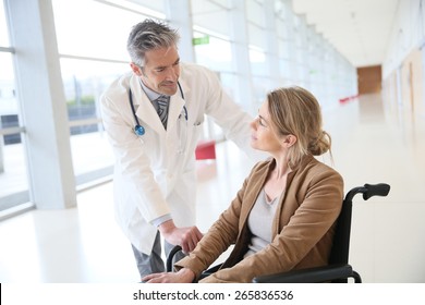 Doctor Talking To Woman In Wheelchair After Surgery