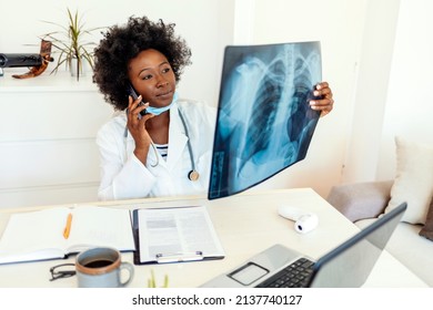 Doctor talks with patient about results while holding an x-ray in hands, a female doctor discusses the results with a patient or colleague via smartphone. Medicine, radiology and healthcare concept. - Powered by Shutterstock