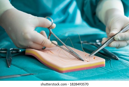 Doctor teaches the technique of suturing and closure on silicone pad. Doctor teaching and suturing practice in basic skills on skin silicone pad. Simple interrupted suture. Vertical mattress suture. - Shutterstock ID 1828493570
